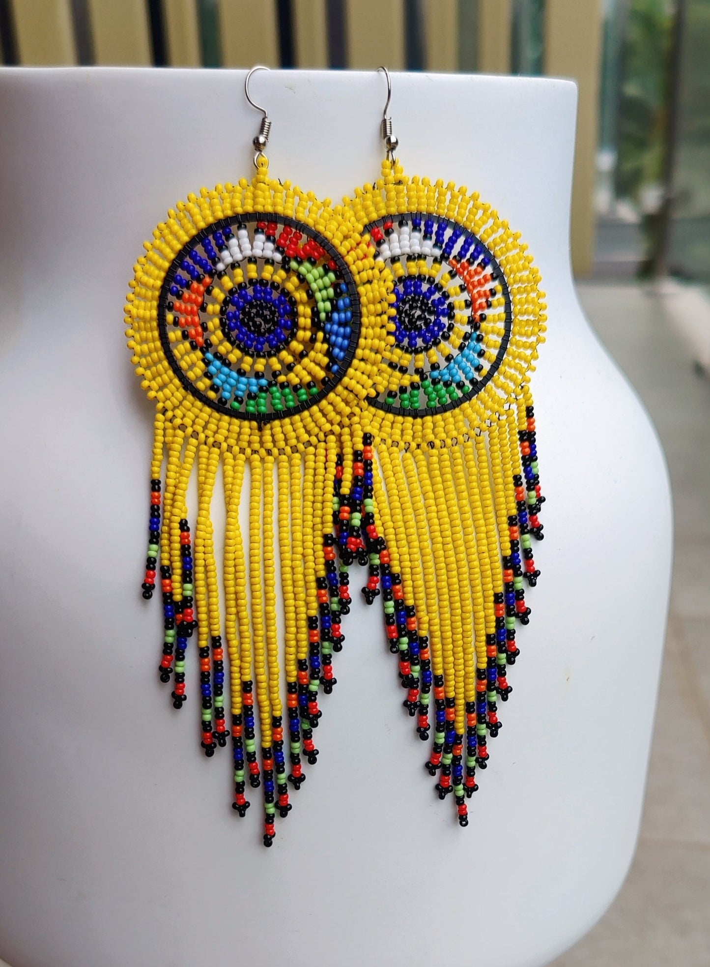 yellow beaded circle with tassels on the bottom end of the earrings